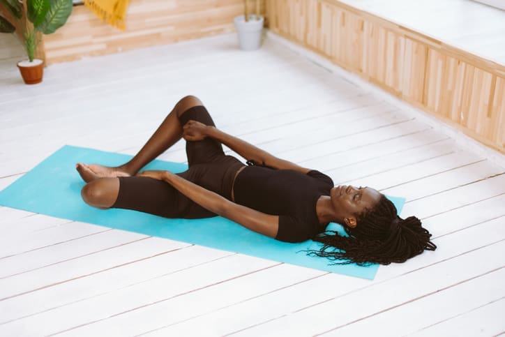 A Black woman relaxes in the reclined butterfly yoga pose