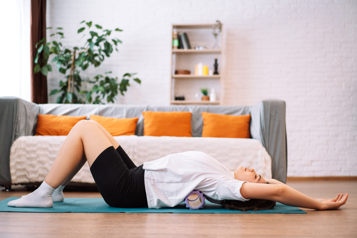 A woman rolls out her back with a foam roller for her fascia
